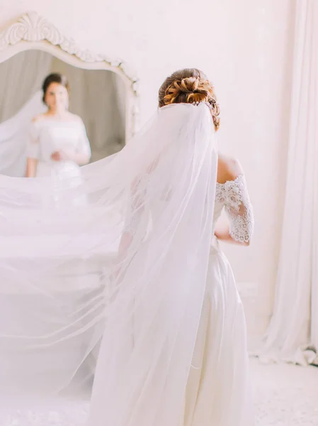 Вид сзади невесты с вуалью на голове, смотрящей в зеркало . — стоковое фото