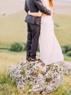 Yeni evliler taş üzerinde duruyor. Bacaklar görünümünü yakın çekim.