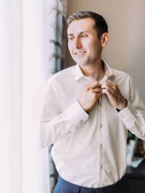 Mutlu damat pencereden bakarken gömleğini kadar düğmelerini.