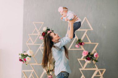 Kadın arka planını çiçekler ile dekore edilmiş ahşap kirişler, gülümseyen bebek yetiştirme.