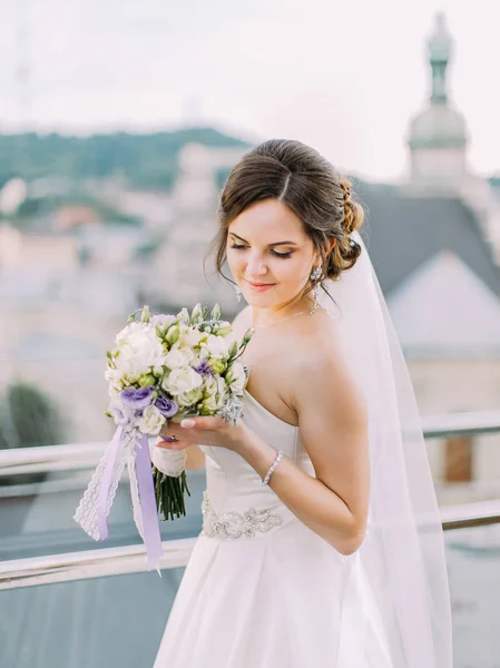 Il ritratto ravvicinato della sposa che tiene e guarda il bouquet di nozze . — Foto Stock