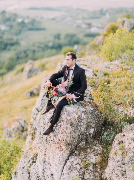 Вид Збоку Нареченого Сидить Скелі Тримає Величезний Букет Барвистих Квітів — стокове фото