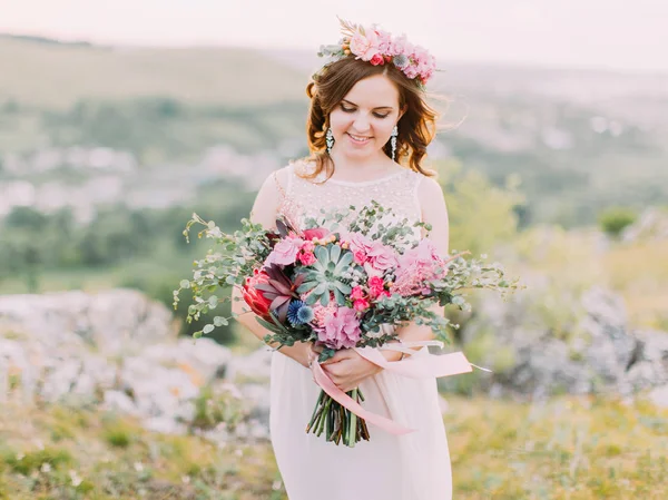 押しながら巨大な結婚式の花束を見て笑顔の花嫁のクローズ アップ水平ビュー. — ストック写真