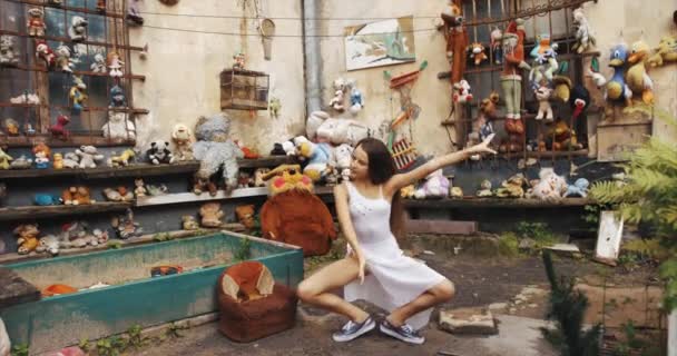 Pequena bailarina linda dançando no antigo jardim decorado com brinquedos vintage e móveis. Imagens de 4K. Vista de comprimento total . — Vídeo de Stock