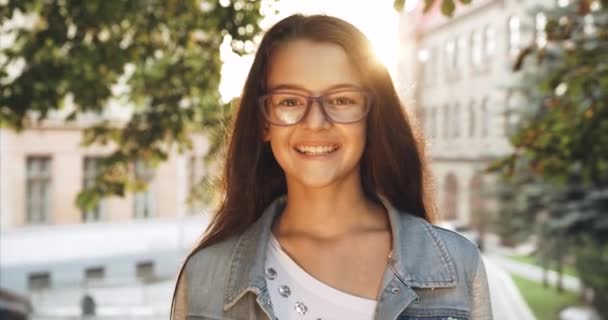 Retrato da criança. Menina em óculos roxos está sorrindo para a câmera em chamas do sol. Filmagem 4k . — Vídeo de Stock
