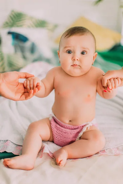 O retrato vertical do bebê nu sentado na planície com o surpport dos pais . — Fotografia de Stock