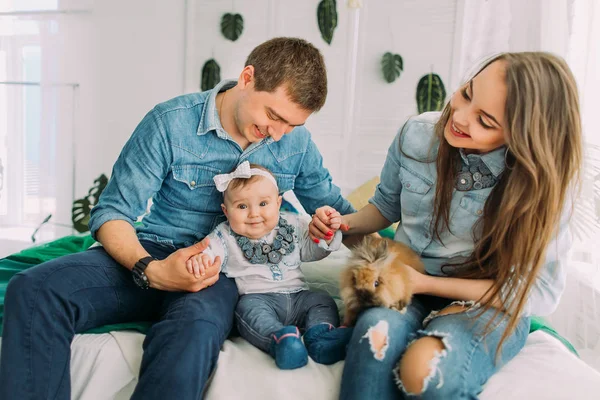 Happy family is sitting on the bed and playing with the babby. Close-up view. — Stock Photo, Image