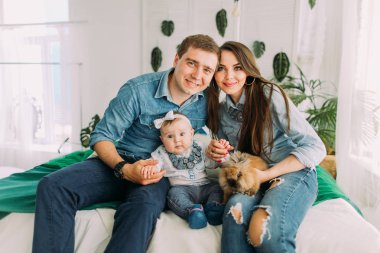 Mutlu aile yatağa oturmuş ve bebek ve tavşan tutarak yatay portresi.