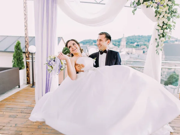 Щасливий наречений стрибає навколо нареченої біля весільної арки . — стокове фото