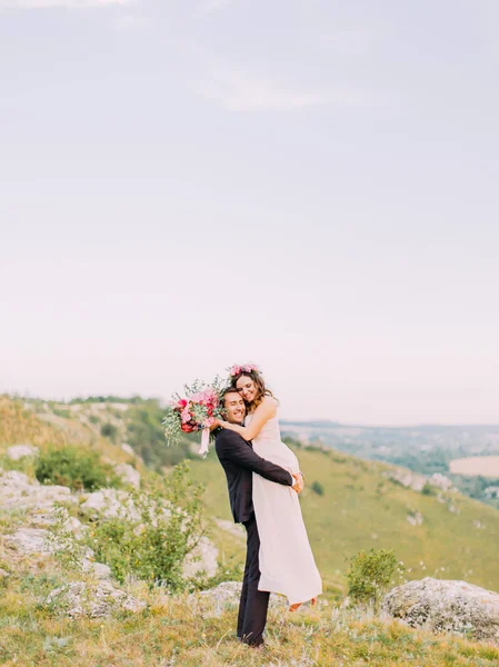 La vista completa del novio llevando a la novia en las montañas . — Foto de Stock