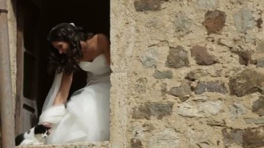 Pencerenin küçük kedi okşayarak siyah kıvırcık saçlı Genç güzel gelin portresi. Sokaktan görüntülemek.