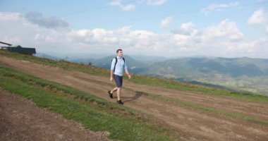 Yalnız yürüme dağlarda. Yakışıklı genç bir sırt çantası ile tepe boyunca onun omuzlarında yürür ve gökyüzüne etrafına bakıyor