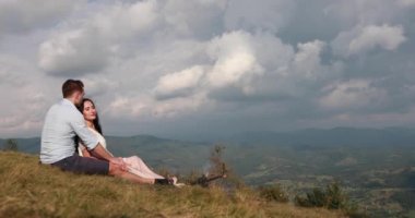 Daha önce muhteşem bir dağ manzaralı bir kamp ateşi tarafından otururken adam güzel bir kadın ihale hugs