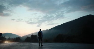 Onu daha önce araba yolculuğu yaparken eveninf dağ yolu üzerinde bir adam hitchhinking silueti