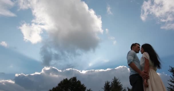Αγάπη στα βουνά. Όμορφος άνδρας αγκαλιάζει γυναίκα τρυφερή στέκεται κάτω από δραματικές βραδινό ουρανό με βαριά σύννεφα — Αρχείο Βίντεο
