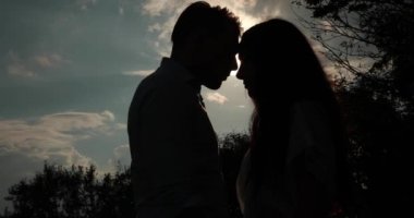 Dağlarda seviyorum. Solhouettes erkek ve kadın akşam güneş ışınlarının öpüşme