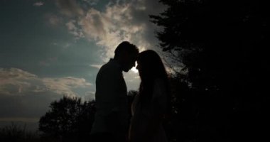 Dağlarda seviyorum. Solhouettes erkek ve kadın akşam güneş ışınlarının öpüşme