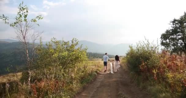 Amore in montagna. L'uomo e Woiman corrono lungo la strada verso l'orizzonte da qualche parte sulla collina mentre il sole splende su di loro. — Video Stock
