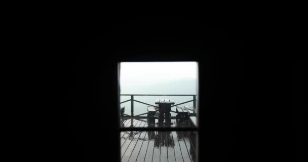Spojrzenie z zewnątrz ciemny dom o deszcz spada na stół i ławki na zewnątrz na ganku — Wideo stockowe