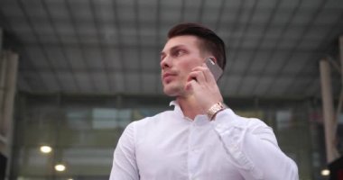 İş yerinde iş adamı. Beyaz tişörtlü yakışıklı genç adam telefonda konuşan ve onun etrafında bir taksi için