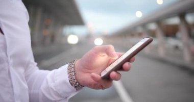 İş yerinde iş adamı. Birisi arar iken beyaz gömlek ve zengin kol saati yakışıklı genç adam onun smartphone içinde bir sayı türleri