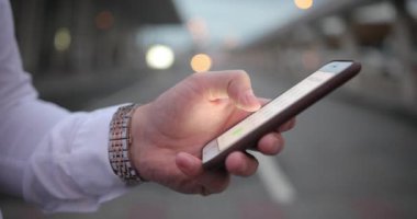 İş yerinde iş adamı. Birisi arar iken beyaz gömlek ve zengin kol saati yakışıklı genç adam onun smartphone içinde bir sayı türleri
