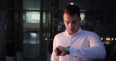 İşadamı bir gezi. Meşgul genç yakışıklı adam etrafında ve dışarıda bir taksi bekleyen onun armwatch görünüyor