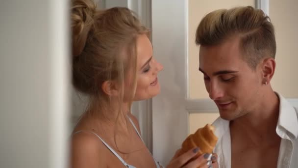 Sexy jovem mulher em lingerie rosa bebe café e come croissant com seu homem pela manhã — Vídeo de Stock