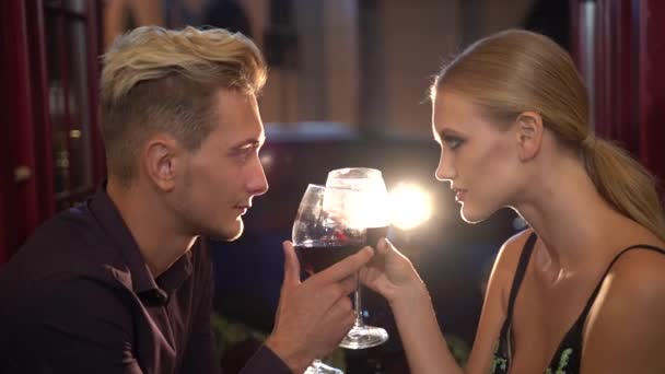 Romantic atmosphere around pretty man and woman drinking wine in the restaurant and looking at each other with passion — Stock Video