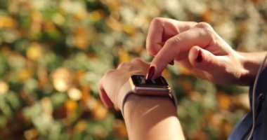Kadın atlet parkında. Kadın cheks bir molası o süre onun smartwatch sabah ışık dolu sonbahar dışarıda eserlerinde park