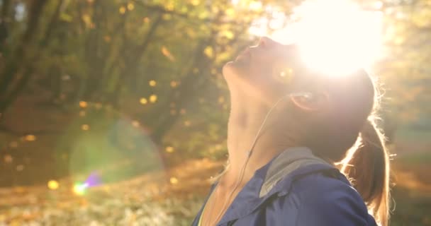 Běžkyně v parku. Žena se těší, padající listy stojící v paprscích ranního slunce a vrhací přestávku po spuštění — Stock video