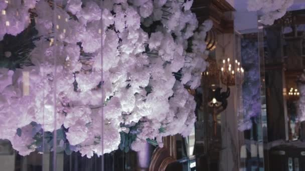 Arredamento e organizzazione di matrimoni al ristorante. Nuvola di rose bianche e crisantemi pende sopra il tavolo principale per gli sposi al ricevimento di nozze — Video Stock