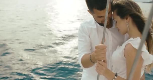 Coppia innamorata di rilassarsi sullo yacht. Vento soffia vestito da donna mentre l'uomo abbraccia il suo tenero in piedi sullo yacht bianco — Video Stock