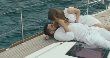 İki yat rahatlatıcı aşık. Kadın ve erkek birbirlerine kendi gezi yatında zevk ihale beyaz giysiler sarılmak giyinmiş