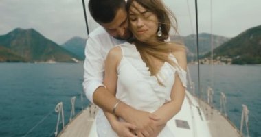 İki yat rahatlatıcı aşık. Kadın ve erkek birbirlerine kendi gezi yatında zevk ihale beyaz giysiler sarılmak giyinmiş