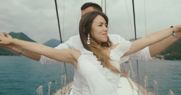 Пара влюбленных отдыхает на яхте. Мужчина и женщина в белой одежде нежно обнимаются, наслаждаясь путешествием на яхте. — стоковое видео