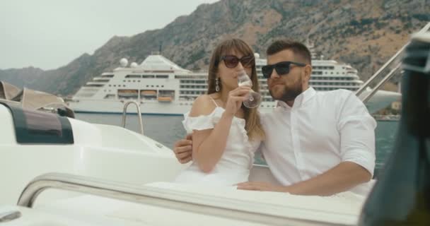 Par i kärlek avkopplande på Lustjakt. Mannen och kvinnan klädd i vita kläder krama varandra anbud och dricker champagne njuter av sin resa på yacht — Stockvideo