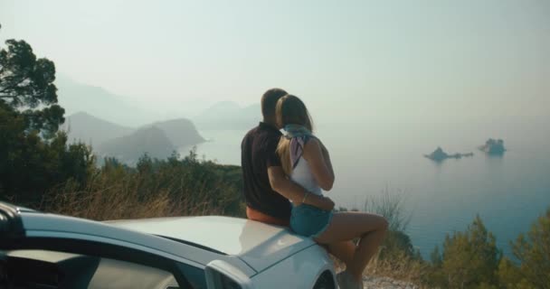 Romantic road trip. Stylish man and woman enjoy beautiful landscape standing before a car somewhere in Montenegro — Stock Video