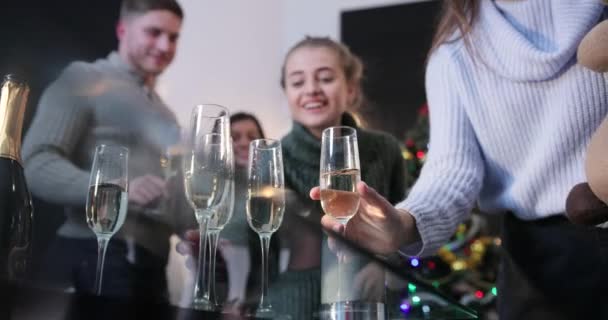 Celebración de Año Nuevo. La gente toma flautas de champán de la mesa mientras bailan ante un árbol de Navidad. — Vídeos de Stock