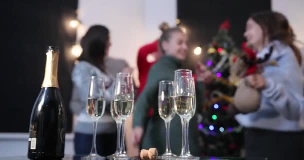 Nyårsfirande. Människor tar champagne flöjter från middagsbordet medan de dansar innan en julgran — Stockvideo