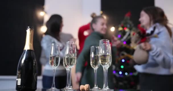 Celebração de Ano Novo. As pessoas tiram flautas de champanhe da mesa de jantar enquanto dançam diante de uma árvore de Natal — Vídeo de Stock