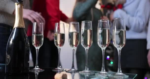 Festeggiamenti di Capodanno. Le persone ballano sullo sfondo mentre la fotocamera si concentra sui flauti di champagne — Video Stock