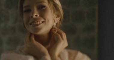 Karadağ düğünde. Geleneksel Avrupa kabul töreni. Resepsiyon sabaha. 4 k. gelin narin ipek elbise içinde otel odasında duran küpe koyar