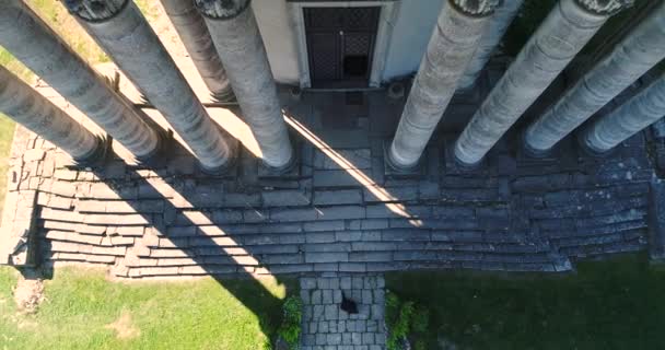 Középkori építészet. Nyári nap. A légi felvétel a személy fekete sétáló belül egy régi Ghotic templom magas col oszlopok és Szent emberek alakja, a tetején. Ukrajna, Pidhirtsi-kastély — Stock videók