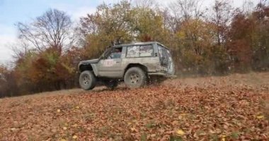 Turistik faaliyetleri, exreme. 4 k. ağır çekim. Aşırı off-road araç Mitsubishi Pajero sürüş hızlı dağ yolda düşmüş yaprakları ile kaplı. Sis tepelerin üstünde