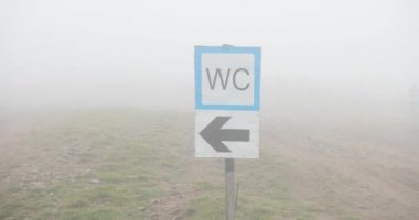Sokak tabelası Sisli havalarda. Wc işareti ile sis kaplı tepede Close-up.