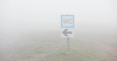 Sokak tabelası Sisli havalarda. Wc işareti ile sis kaplı tepede Close-up