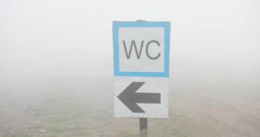Sokak tabelası Sisli havalarda. Wc işareti ile sis kaplı tepede Close-up.