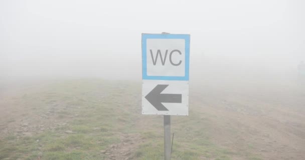 Panneau de rue par temps brumeux. Gros plan de la pancarte WC sur la colline couverte de brouillard . — Video