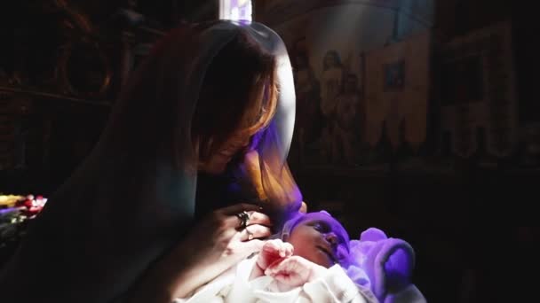 Православие, христианство, церковь. Мать выглядит как святая Мария, стоящая со спящим ребенком на руках в церкви. — стоковое видео
